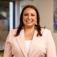 Woman in pink blazer smiling indoors with office background